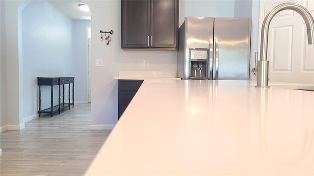 kitchen with stainless steel fridge, dark brown cabinetry, light hardwood / wood-style floors, and sink