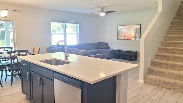 kitchen featuring dishwasher, sink, light hardwood / wood-style floors, a center island with sink, and ceiling fan with notable chandelier