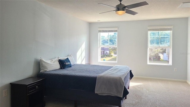 bedroom with multiple windows, a textured ceiling, carpet floors, and ceiling fan