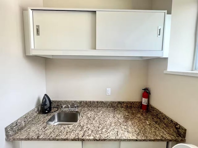 kitchen with white cabinets, sink, and stone counters