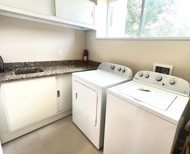 laundry area with cabinets, light tile patterned floors, sink, and washing machine and clothes dryer