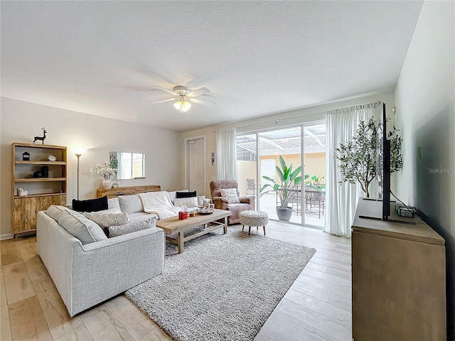 living room featuring a textured ceiling, light hardwood / wood-style floors, and ceiling fan