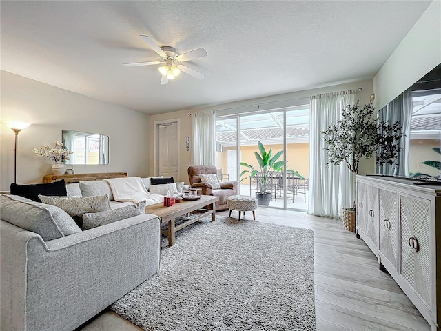 living room with a textured ceiling, light hardwood / wood-style floors, and ceiling fan