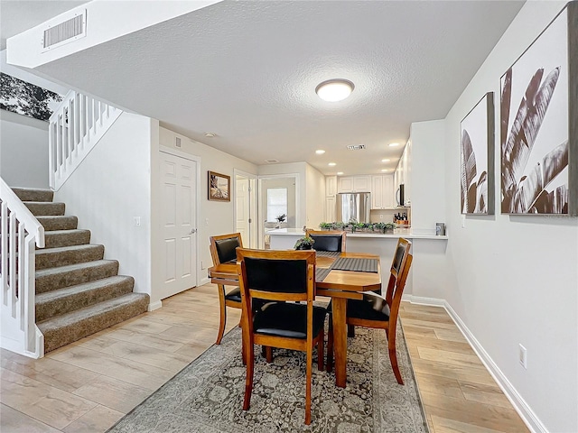 dining area with a textured ceiling and light hardwood / wood-style flooring