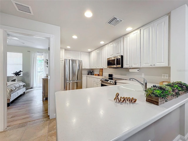 kitchen with white cabinets, appliances with stainless steel finishes, light tile patterned floors, and sink