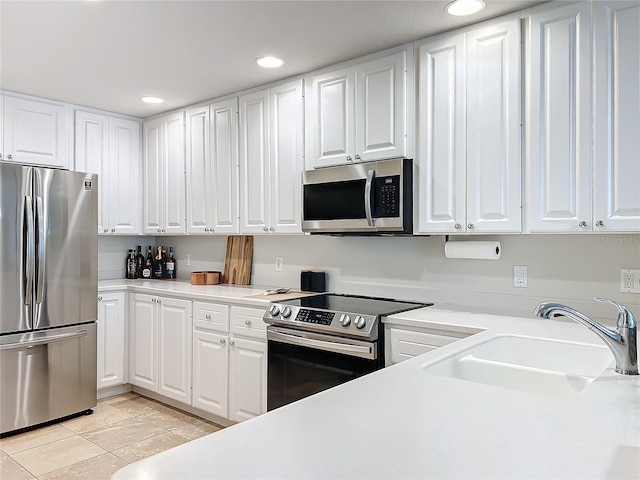 kitchen featuring sink, white cabinets, stainless steel appliances, and light tile patterned floors