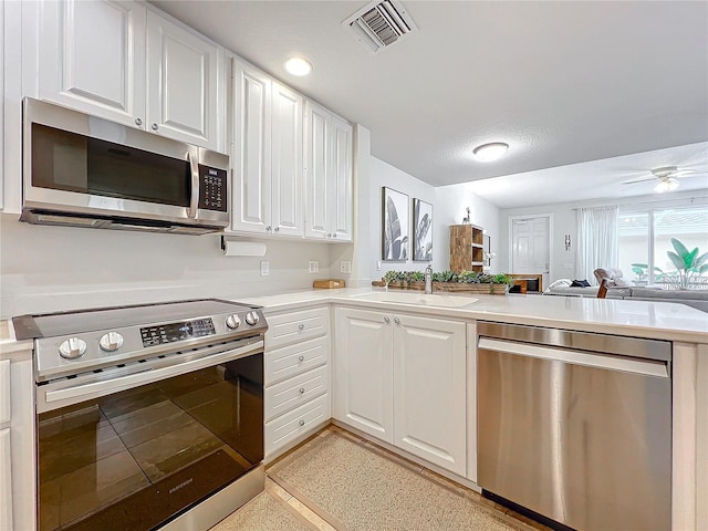 kitchen featuring kitchen peninsula, appliances with stainless steel finishes, white cabinetry, and sink