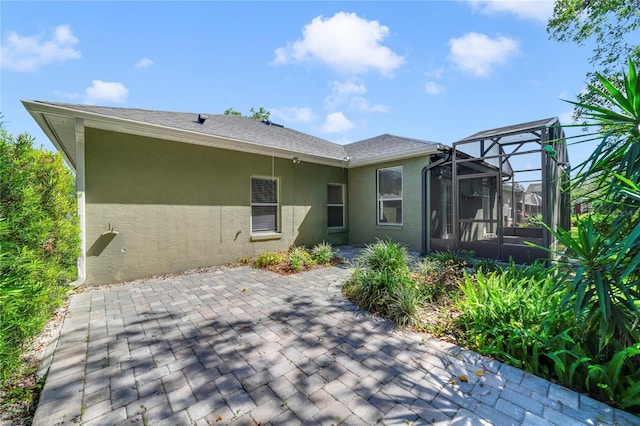2961 Cedar Glen Pl, Oviedo, FL 32765 - rear view of house with a patio, stucco siding, glass enclosure, and a shingled roof