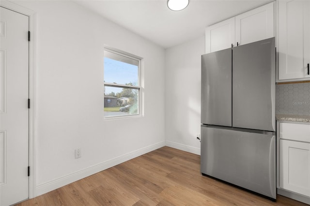 kitchen with white cabinets, stainless steel fridge, and backsplash