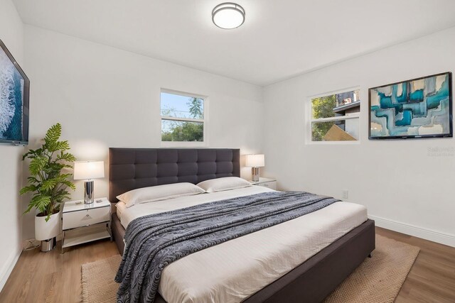 bedroom with wood-type flooring and multiple windows