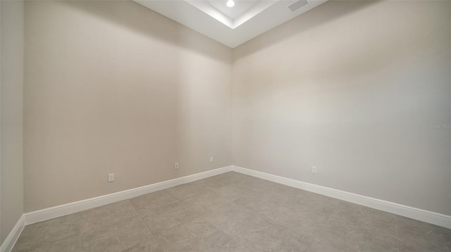 unfurnished room with a tray ceiling, visible vents, baseboards, and recessed lighting