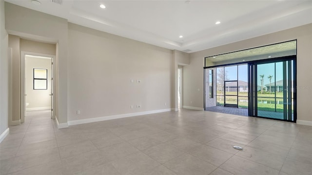 empty room featuring baseboards, a raised ceiling, recessed lighting, and light tile patterned flooring