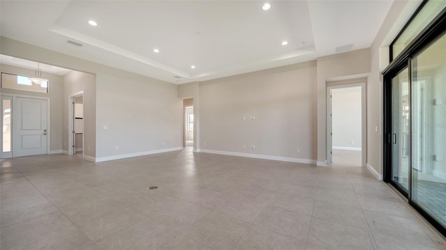 unfurnished room with a tray ceiling, visible vents, and a healthy amount of sunlight