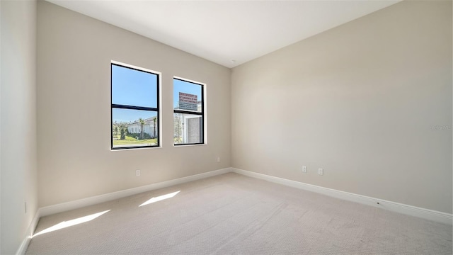 unfurnished room with baseboards and light colored carpet