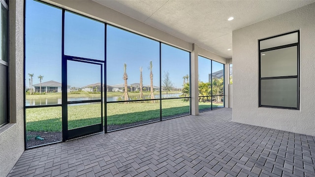 unfurnished sunroom featuring a water view and a residential view
