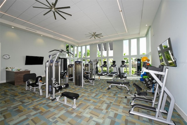 exercise room featuring a ceiling fan, a wealth of natural light, a high ceiling, and carpet