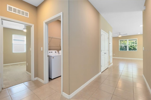 hall with washer and dryer and light tile patterned flooring