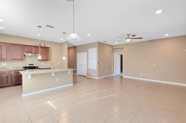 kitchen with light stone counters, a breakfast bar, ceiling fan, a center island with sink, and stainless steel electric range