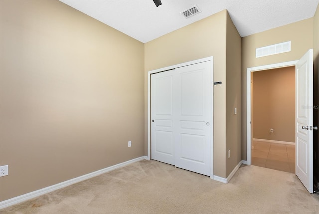 unfurnished bedroom with ceiling fan, light carpet, and a closet