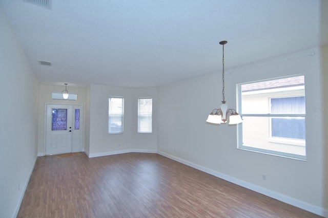 spare room featuring wood-type flooring and a chandelier