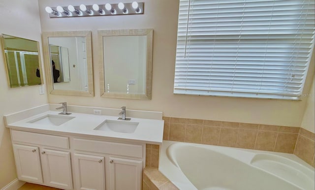 bathroom with vanity and tiled tub