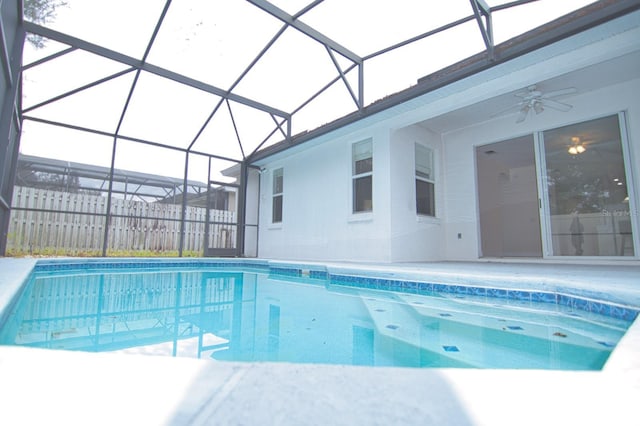 view of swimming pool with a lanai and ceiling fan