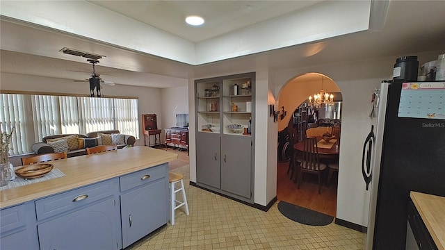 kitchen featuring stainless steel refrigerator, pendant lighting, a notable chandelier, and blue cabinets