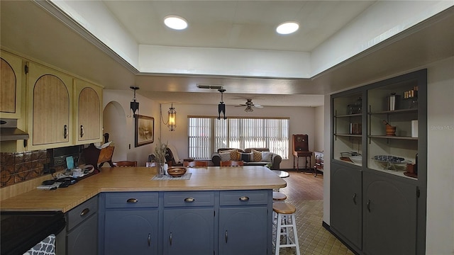 kitchen with kitchen peninsula, black stove, blue cabinets, and ceiling fan