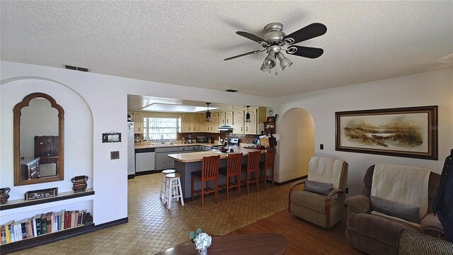 living room featuring ceiling fan, a textured ceiling, and light wood-type flooring