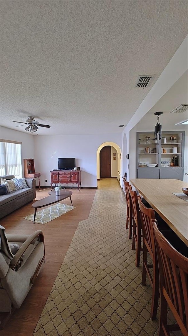 living room with hardwood / wood-style floors, ceiling fan, and a textured ceiling