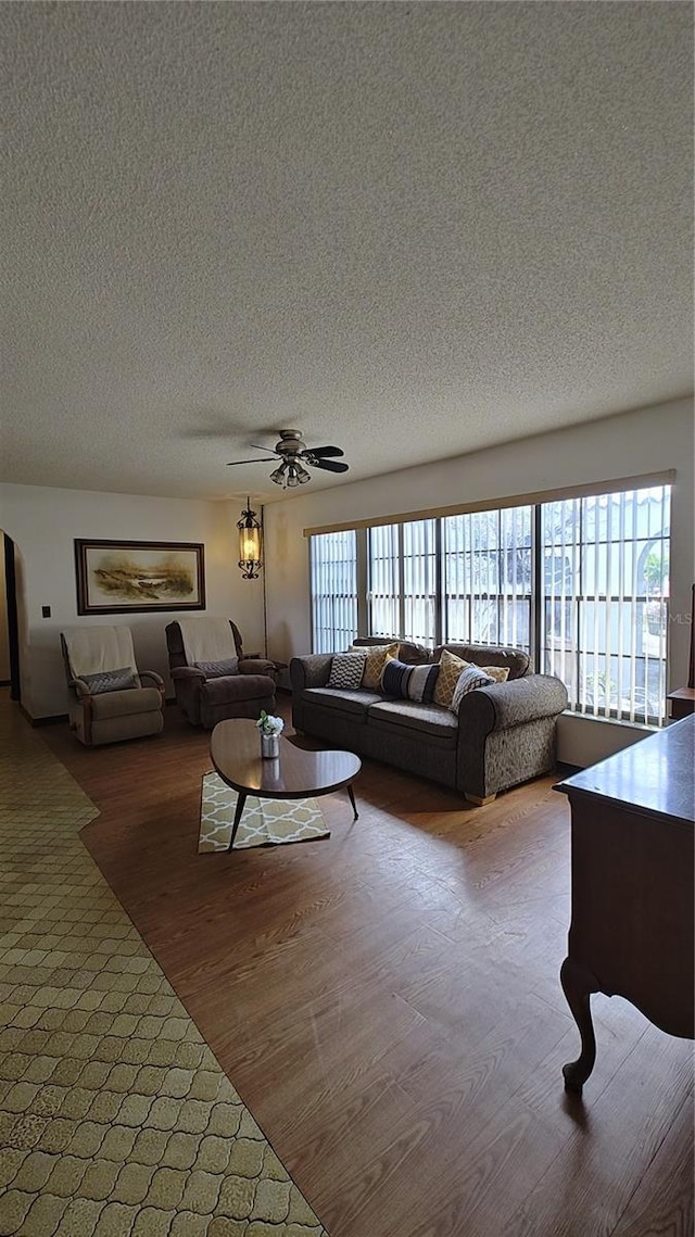 living room featuring ceiling fan, hardwood / wood-style floors, and a textured ceiling