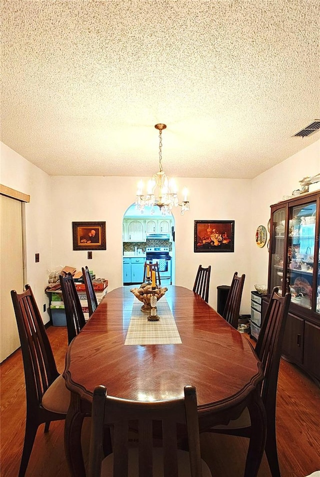 dining space with hardwood / wood-style floors, a textured ceiling, and an inviting chandelier