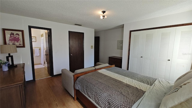 bedroom featuring a textured ceiling, connected bathroom, and dark wood-type flooring