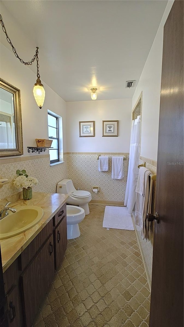 bathroom with a bidet, toilet, vanity, tile walls, and a shower with shower curtain