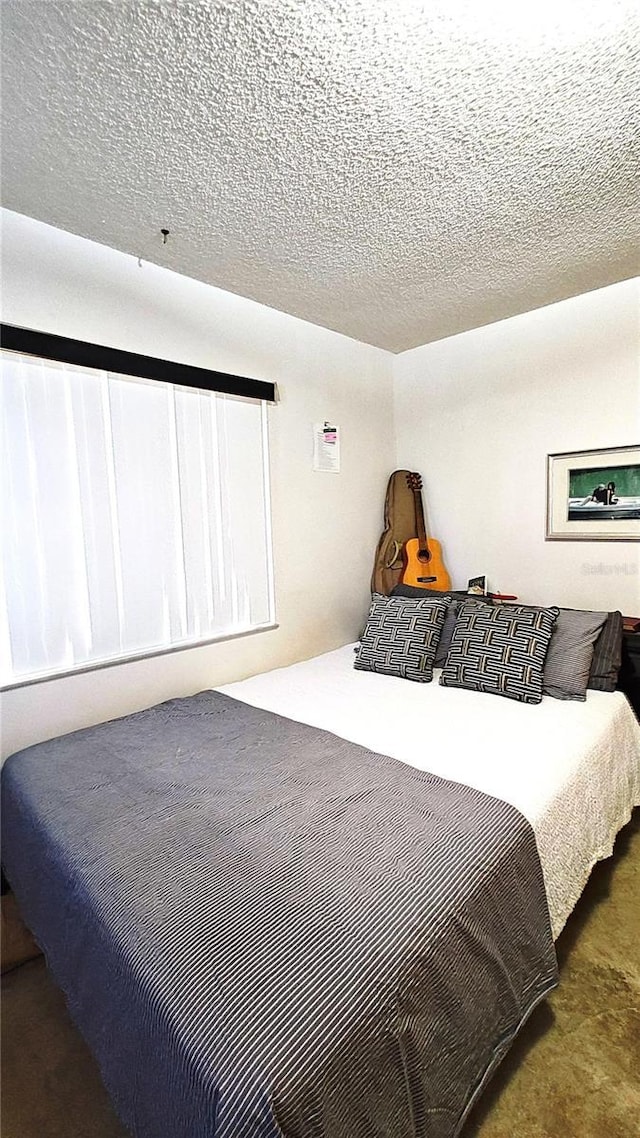 bedroom featuring a textured ceiling and dark carpet