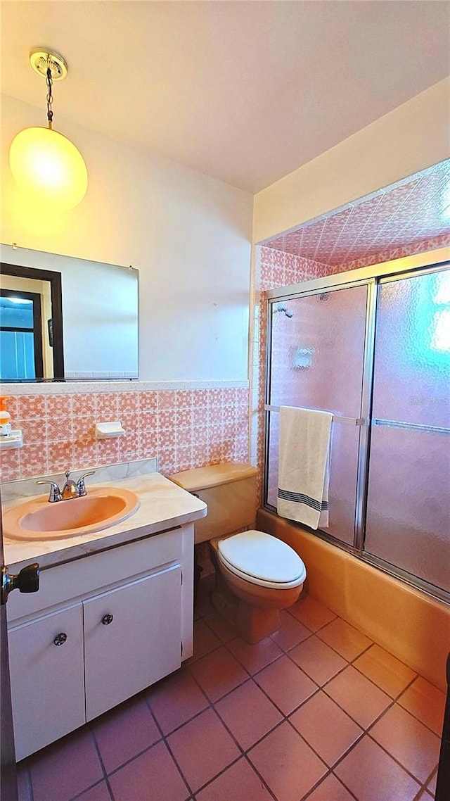 full bathroom with tile patterned floors, vanity, tile walls, enclosed tub / shower combo, and toilet