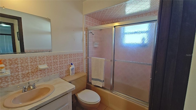 full bathroom with vanity, enclosed tub / shower combo, tile walls, and toilet