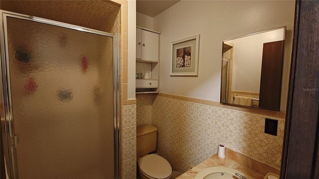 bathroom with an enclosed shower, toilet, and tile walls