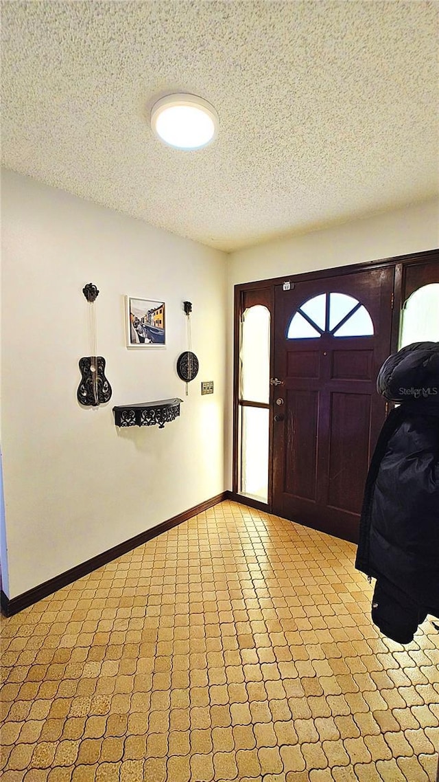 entrance foyer with a textured ceiling, light colored carpet, and a healthy amount of sunlight