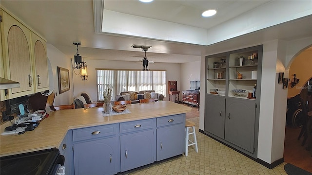 kitchen featuring kitchen peninsula, stove, pendant lighting, and blue cabinets