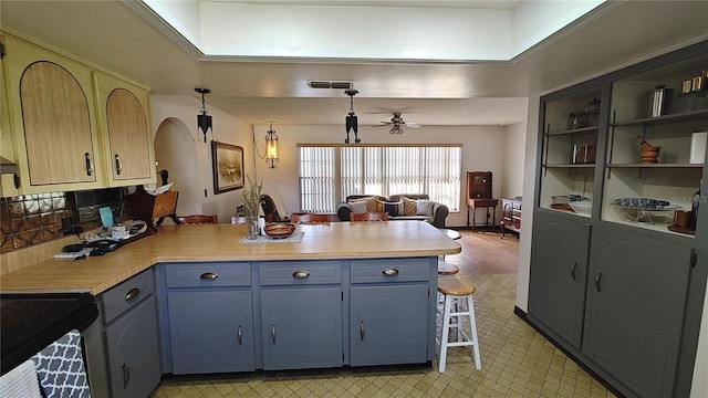 kitchen featuring kitchen peninsula, blue cabinets, ceiling fan, decorative light fixtures, and black range with electric stovetop