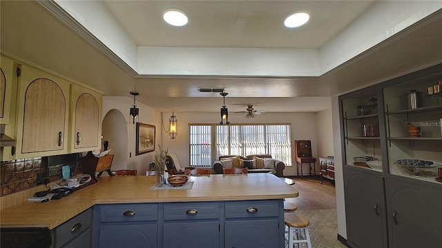 kitchen featuring blue cabinetry, ceiling fan, kitchen peninsula, pendant lighting, and custom exhaust hood