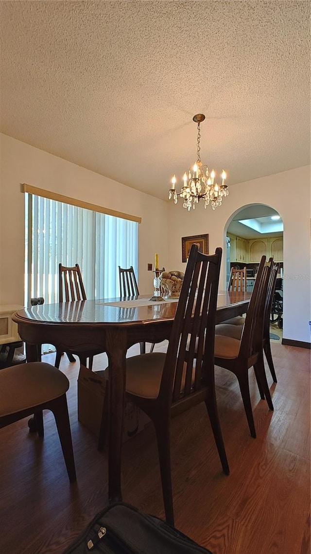 dining area with hardwood / wood-style floors, a textured ceiling, and an inviting chandelier