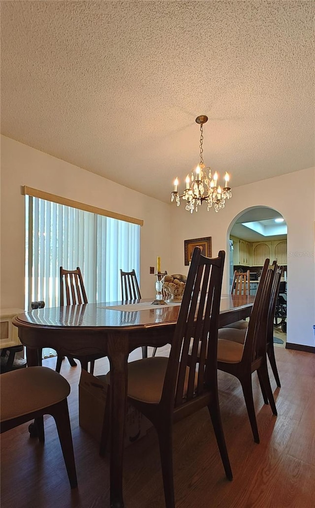 dining area featuring a textured ceiling, hardwood / wood-style flooring, and an inviting chandelier