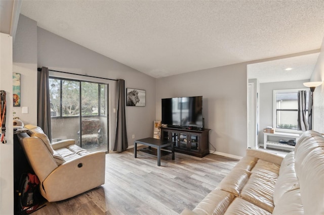 living room with light hardwood / wood-style floors, a textured ceiling, and lofted ceiling