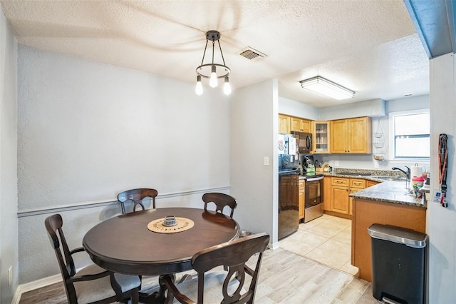 dining space featuring sink, a textured ceiling, and light wood-type flooring