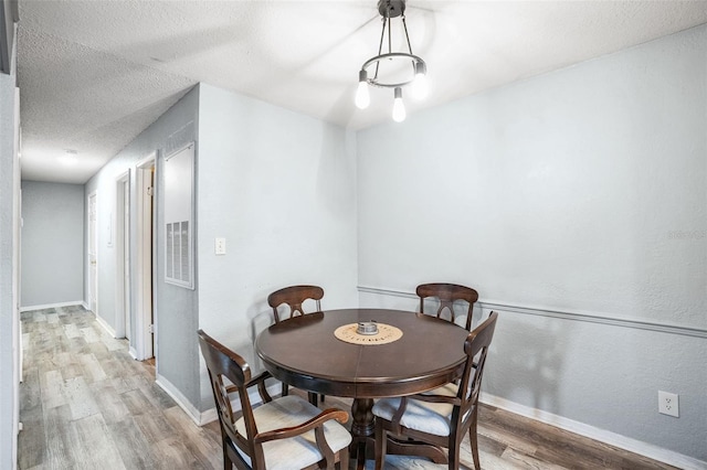 dining space featuring a textured ceiling and hardwood / wood-style flooring