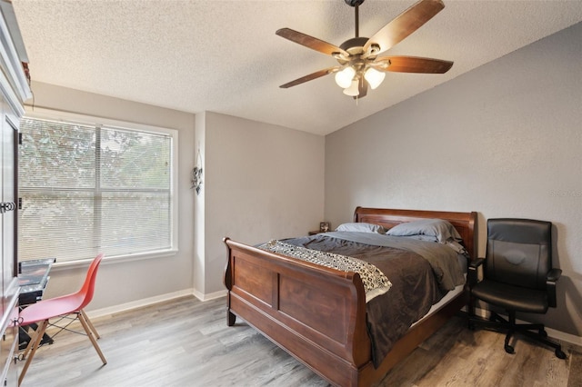 bedroom with a textured ceiling, ceiling fan, and light hardwood / wood-style floors