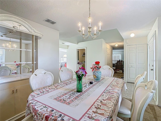 dining space with a textured ceiling and an inviting chandelier