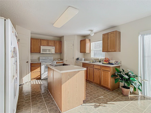 kitchen featuring a kitchen island with sink, sink, dark tile patterned floors, and white appliances